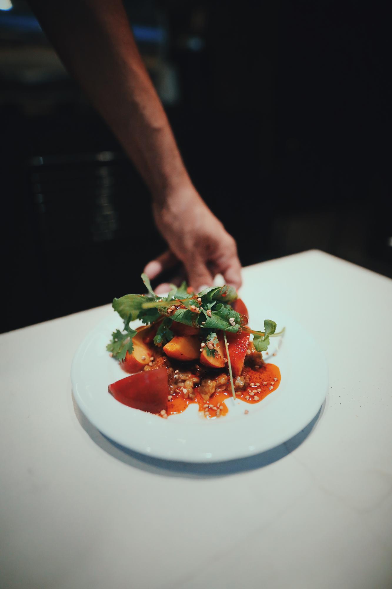 Close-up of hands plating a modern dish in a studio kitchen